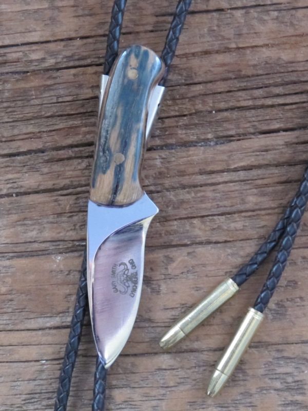A manly knife shaped bolo tie finished off with dark ivory. Bark mammoth bolo tie